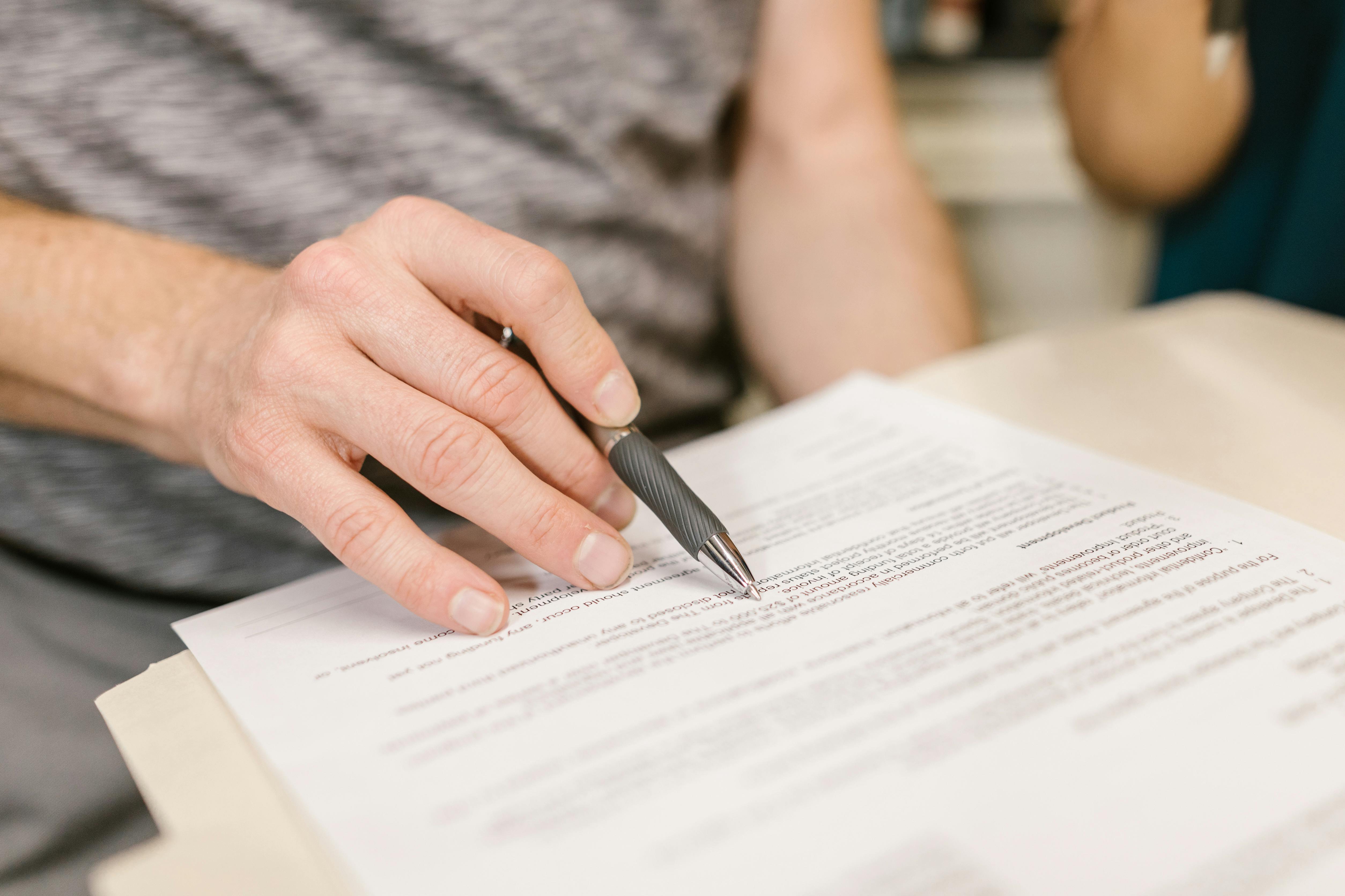 A person reviewing paperwork with a pen.