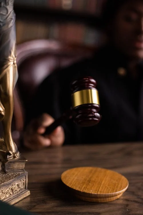 A polished wooden gavel about to strike the sound block.