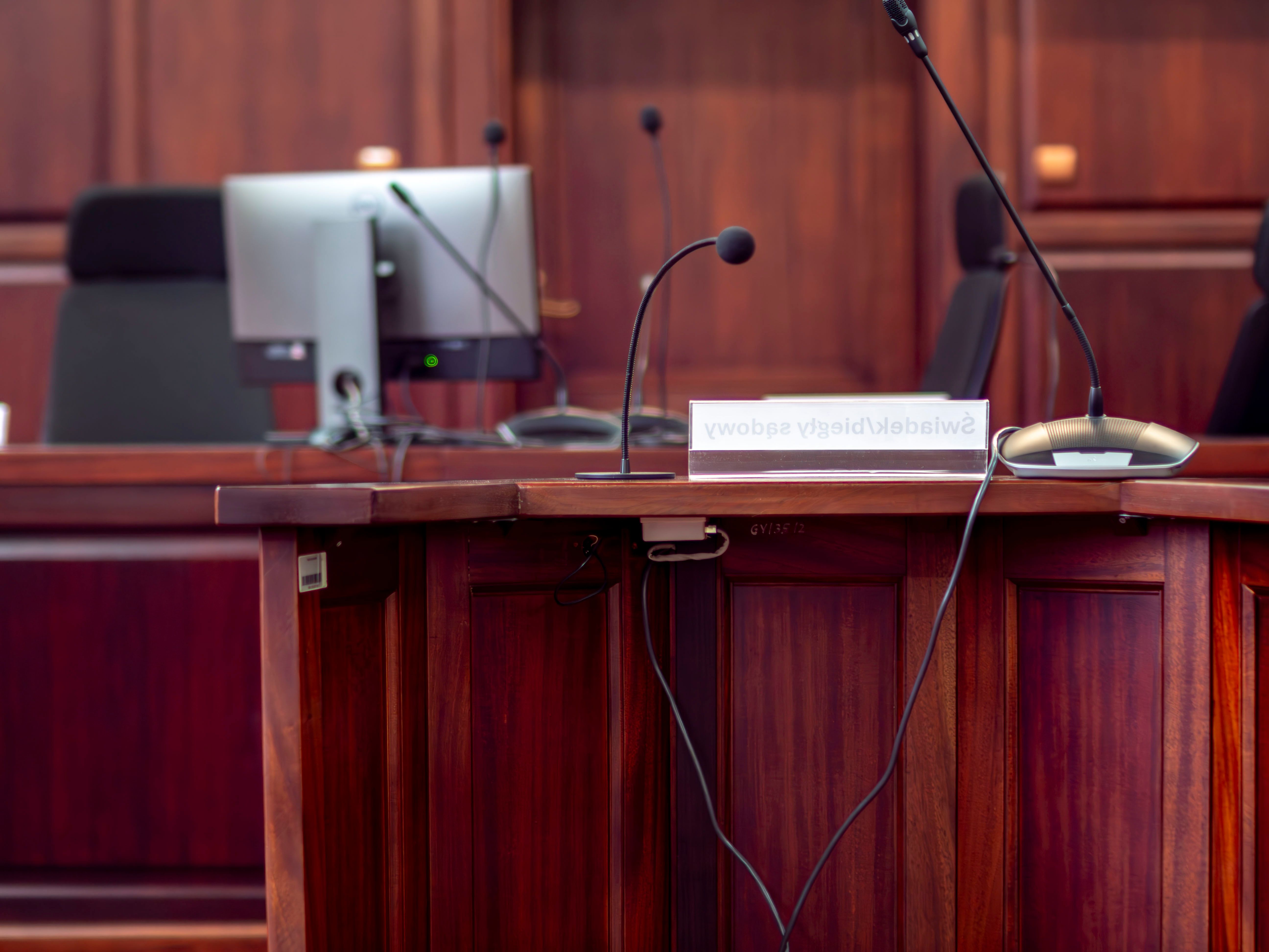 Close-up of a wooden podium with microphones in a courtroom setting