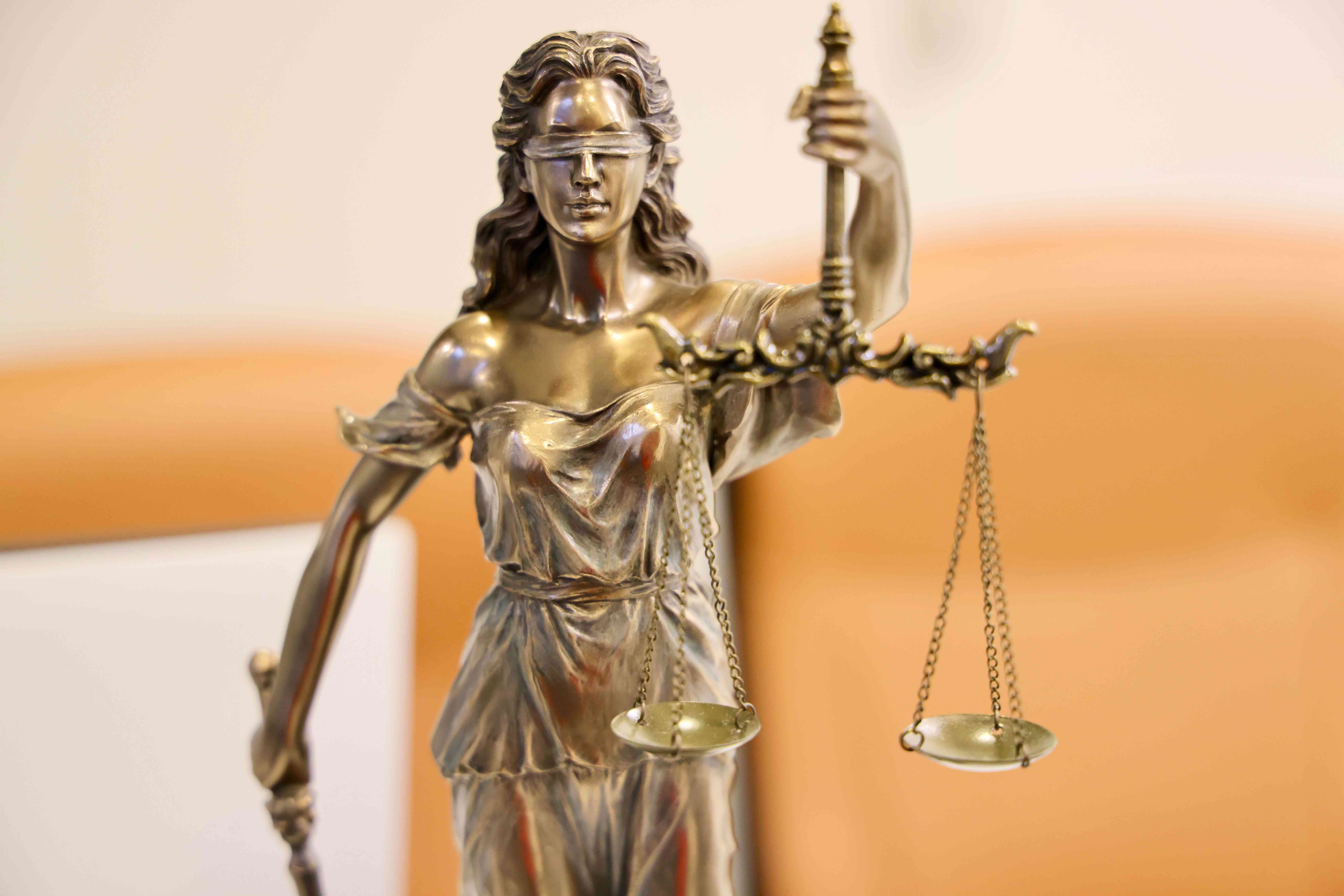 A brass statue of lady justice blindfolded and holding a set of scales.