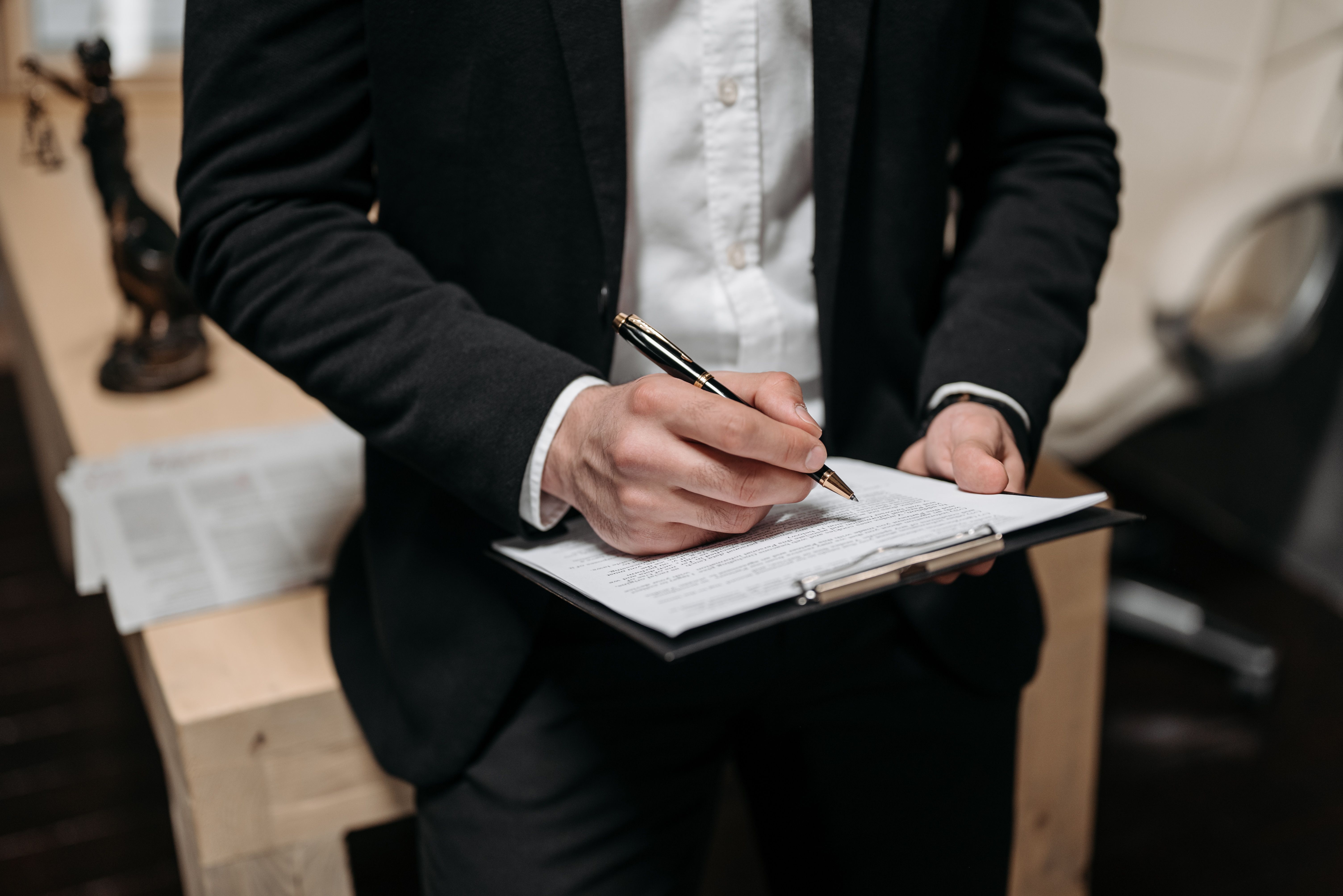 Business professional signing a contract on a clipboard.